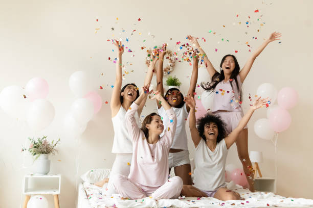 istock Happy diverse girls having fun on bed throw confetti up 1190347725