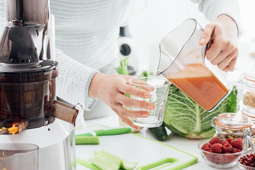 Woman pouring some fresh homemade juice in a glass, healthy food and fitness concept