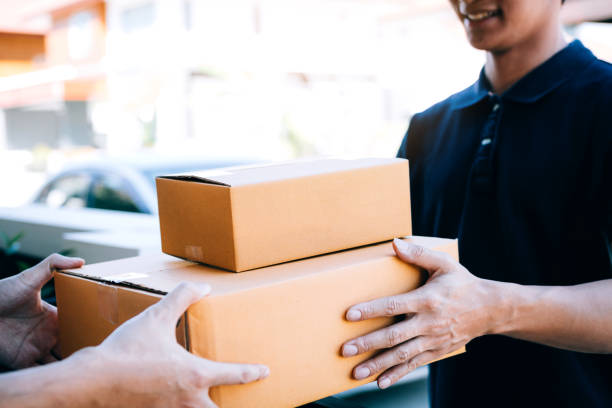 istock Asian cargo carrier holds a cardboard box with the package inside and the recipient is signing the package. 1190352812