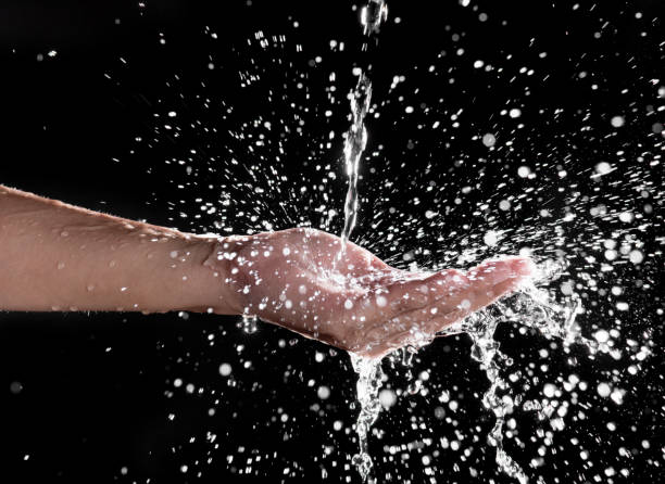 istock Hand and splashing water on black background 1190353907