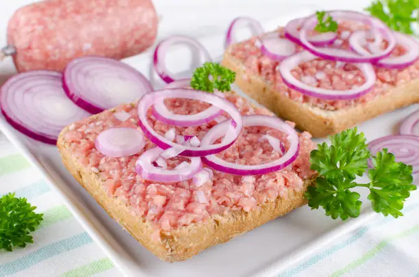german food mett ground pork, raw meat with onion and parsley, selective focus