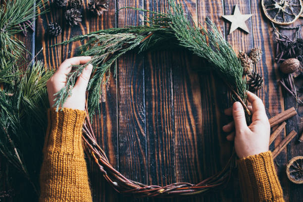 female hands making christmas wreath on dark wood background - lone cypress tree imagens e fotografias de stock