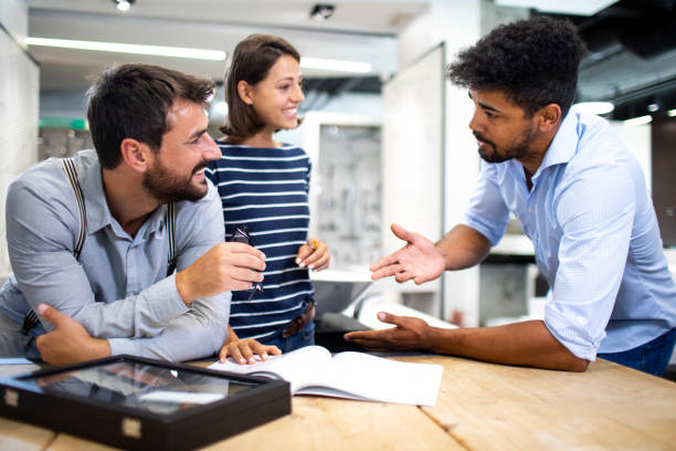 istock Shopkeeper briefing customers about products near the desk with display case with samples 1190357100