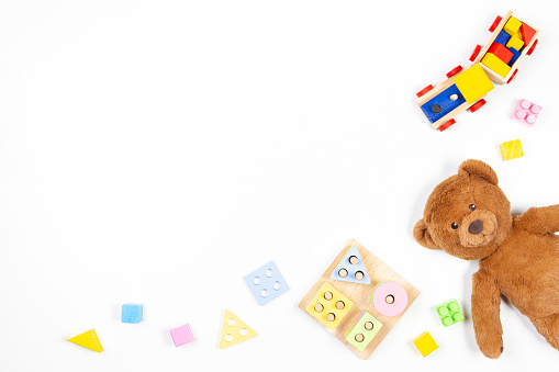 Baby kids toys background. Wooden educational geometric stacking blocks shape color recognition puzzle toy, wooden train, teddy bear and colorful blocks on white background