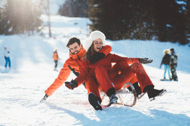 Joyful couple sledding on winter holiday