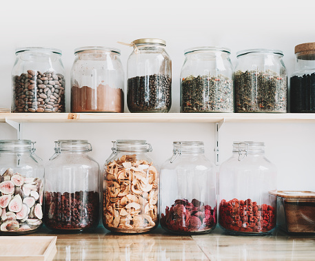 Organic bulk products in zero waste shop. Foods storage in kitchen at low waste lifestyle. Dried berries and fruits in glass jars on shelves. Eco friendly shopping in plastic free grocery store.