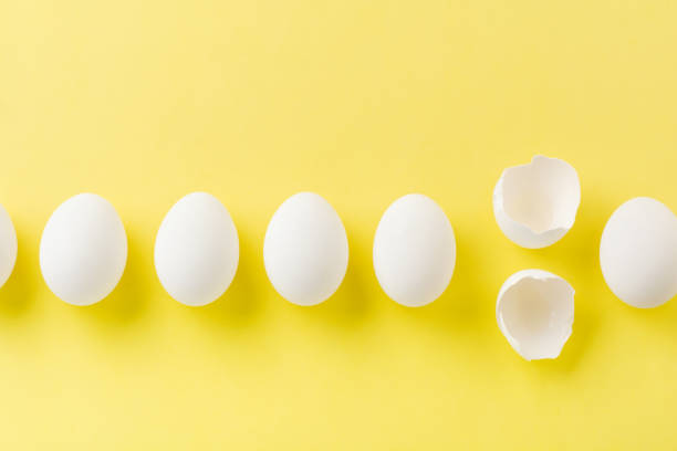 istock White raw chicken eggs lying in horizontal row with broken egg on yellow background. Top view. 1190361947