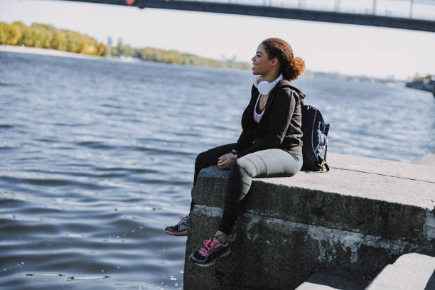 istock Cheerful Afro American lady sitting by the river 1190362613