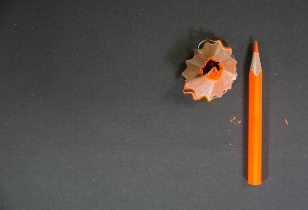 istock orange color pencil with its orange color scrape on black background 1190365624