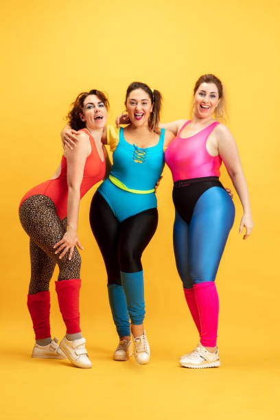 istock Young caucasian plus size female models training on yellow background 1190367058