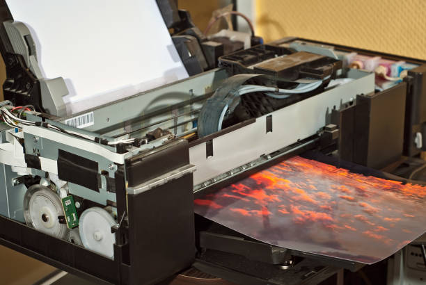 istock Old broken printer in workshop. The concept of cleaning and calibrating printers. Sunset and red sky with clouds in the photo. Picturesque nature photo printed on printing equipment. 1190367296