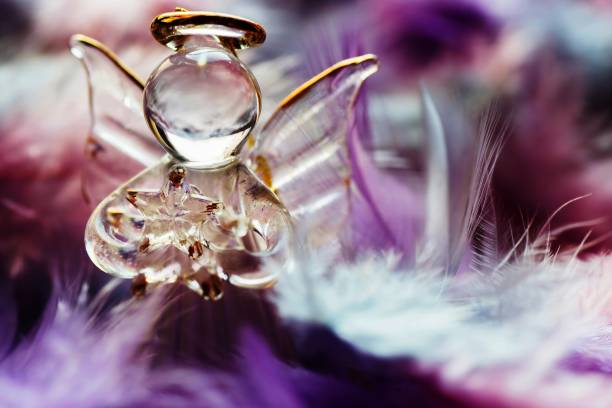 Glass and golden guardian angel figurine with star on feather background. Christmas decoration.