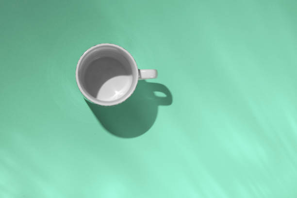istock Empty tea cup on mint paper background. Coffee mug from above. Minimal concept Long shadow with reflections. Flat lay, top view. 1190372115
