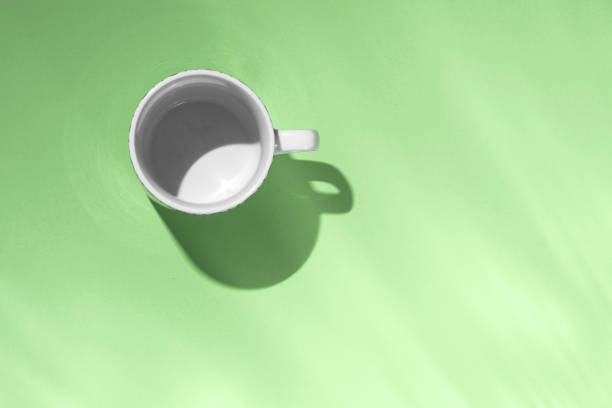 istock Empty tea cup on green paper background. Coffee mug from above. Minimal concept Hard deep shadow. Flat lay, top view. 1190372297
