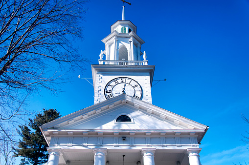 The iconic clock tower on the south congregational church in the town of Kennebunkport Maine on a sunny blue sky early winter day.