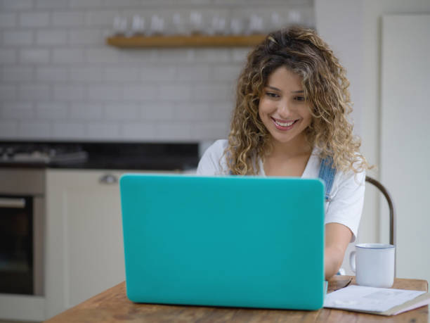 istock Beautiful young woman working from home using laptop while drinking a coffee 1190377036