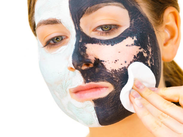 istock Girl remove black white mud mask from face 1190378956