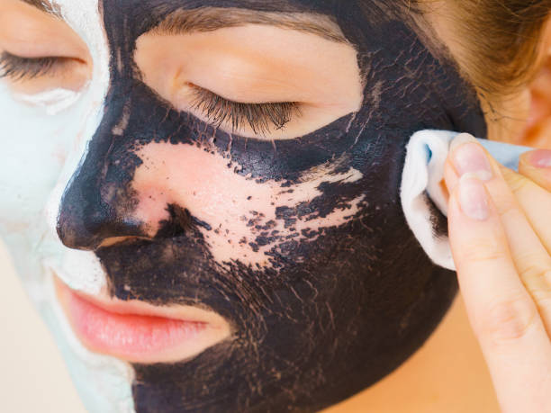 istock Girl remove black white mud mask from face 1190380396