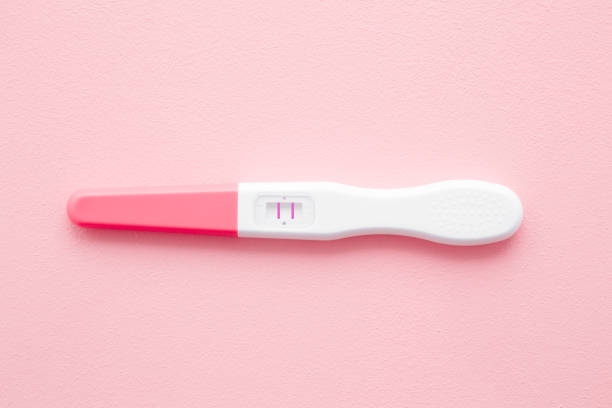Pregnancy test with two stripes on pastel pink background. Positive result. Closeup. Top down view. Pregnancy test with two stripes on pastel pink background. Positive result. Closeup. Top down view. family planning stock pictures, royalty-free photos & images