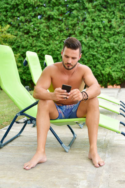 istock Young man on a sun lounger by the pool is using a cellphone 1190382424