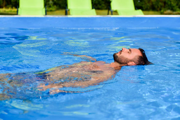 istock Young man floating in the pool enjoys and relaxes 1190383795