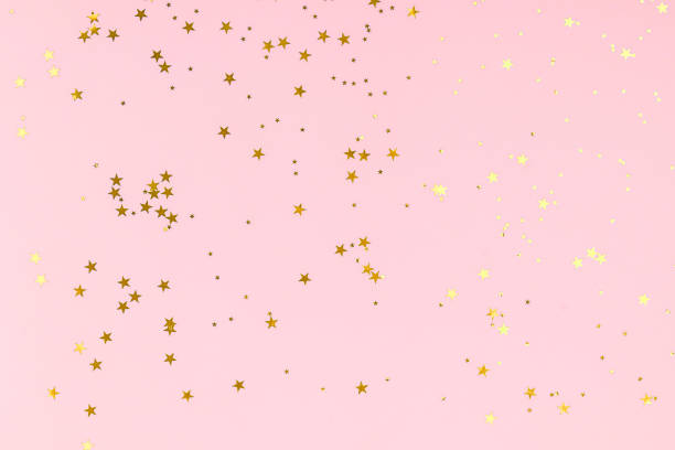 istock Golden stars glitter confetti on pink background. Festive backdrop. 1190383864