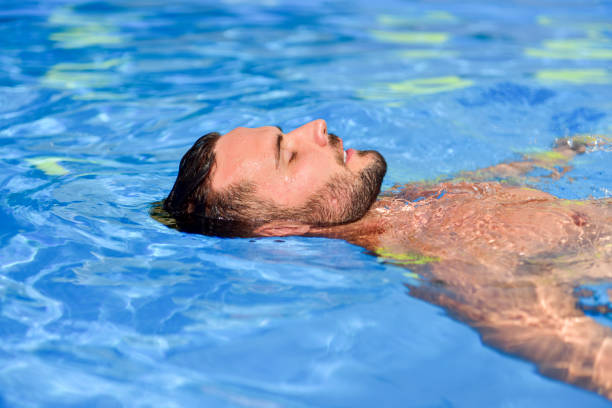 istock Young man floating in the pool enjoys and relaxes 1190384068