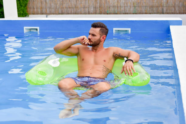 istock Young man enjoying a floating chair in the pool 1190384907