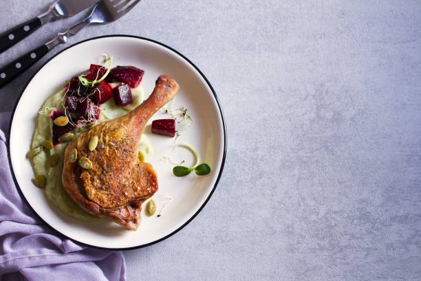 istock Roast duck leg with mashed green vegetables, beetroot, and pumpkin seeds on light gray background 1190387841