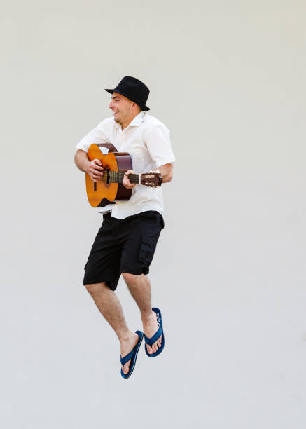 istock Man in sun hat jumping with guitar 1190388601