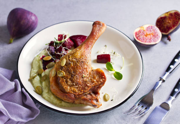 Roast duck leg with mashed green vegetables, beetroot, and pumpkin seeds on light gray background Roast duck leg with mashed green vegetables, beetroot, and pumpkin seeds on light gray background confit stock pictures, royalty-free photos & images