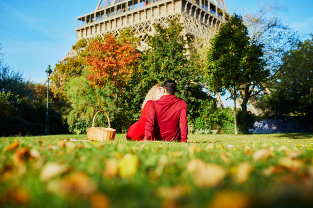 romantic couple having picnic on the grass near the eiffel tower - paris france eiffel tower love kissing imagens e fotografias de stock