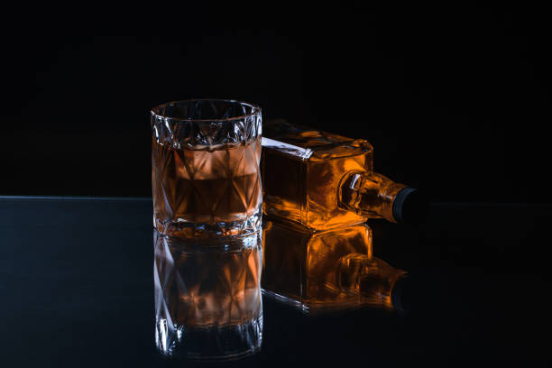 istock Whiskey in glass with ice orange background 1190390157