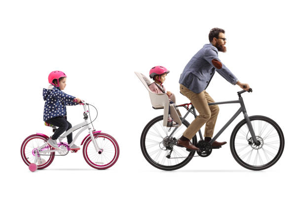 father riding a bicycle with a child seat and a little girl riding a bicycle behind - helmet bicycle little girls child imagens e fotografias de stock
