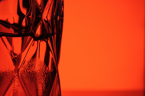 Beautiful glass for whiskey on a red background close-up.