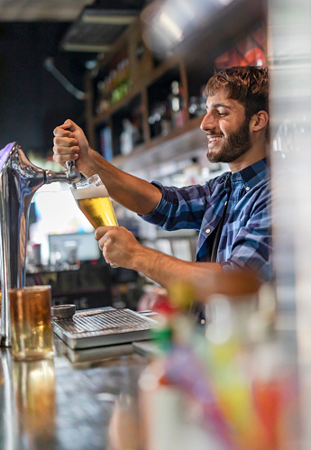 Barman filling fresh beer in a glas at pub