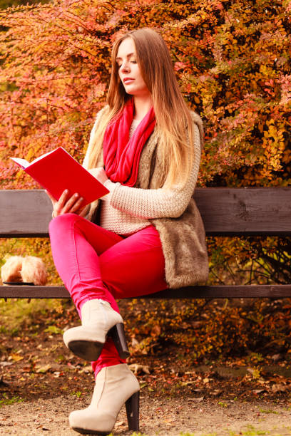 istock Woman relaxing in autumnal park reading book 1190393206