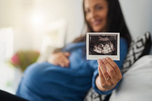 Look who's coming soon Portrait of a pregnant woman holding an ultrasound scan midsection photos stock pictures, royalty-free photos & images