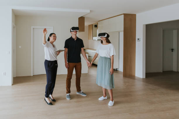 Estate agent with young couple wearing VR headsets in new apartment stock photo