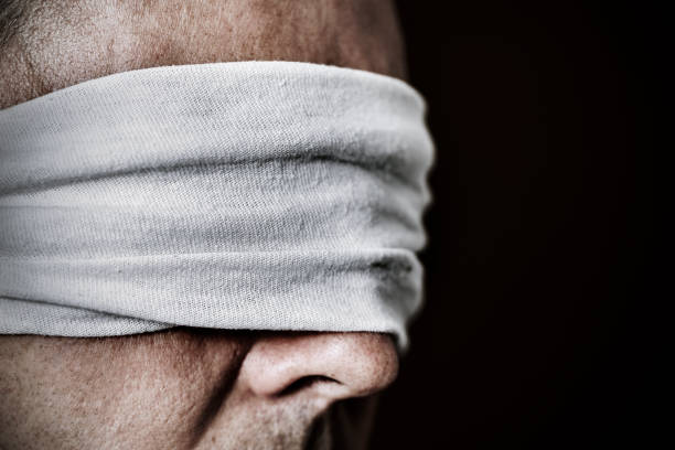 young man with a blindfold in his eyes closeup of a young man with a blindfold in his eyes, as a symbol of oppression or repression, with a dramatic effect kidnapping stock pictures, royalty-free photos & images