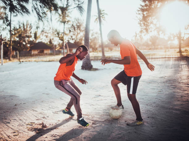 african teenager  playing soccer - beach football imagens e fotografias de stock