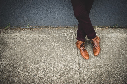 Man leaning on building, shoes in focus