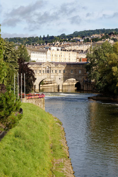 The Georgian bridge with shops and surrounding buildings. River Avon and weir. Long view along the river with boats moored.