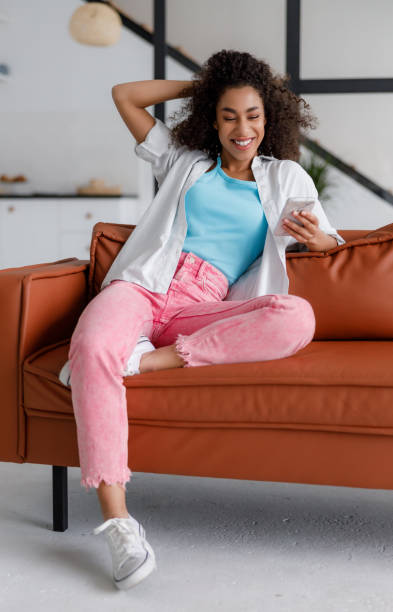 istock Joyful Afro American lady using smartphone at home 1190409659