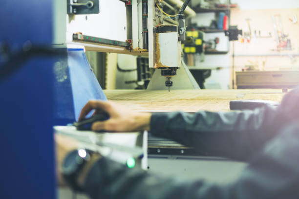 istock Engineer making settings on remote control of CNC wood milling machine for cutting wood 1190410090