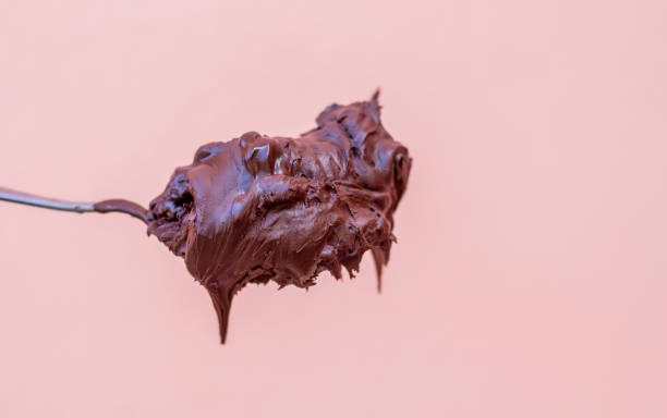 istock Dark chocolate in spoon on pink background. 1190412357
