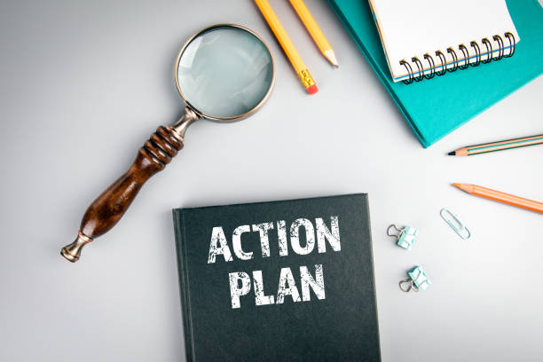 istock Action Plan. Black book cover and magnifying glass 1190414767