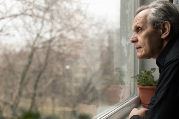 istock an elderly man is sick watching a seasonal bird fly from a window 1190417312