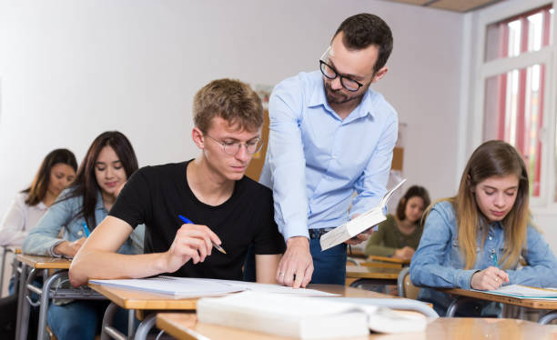 istock Young boy is writing test and teacher is explaining about questions 1190420242