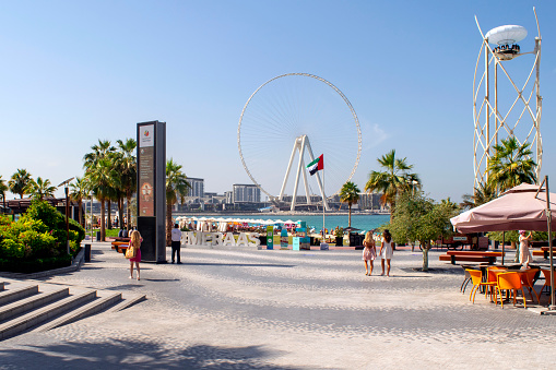 Dubai / UAE - November 7, 2019: JBR. Jumeirah Beach Residence with tourists and view of Bluewaters island. Urban beach.